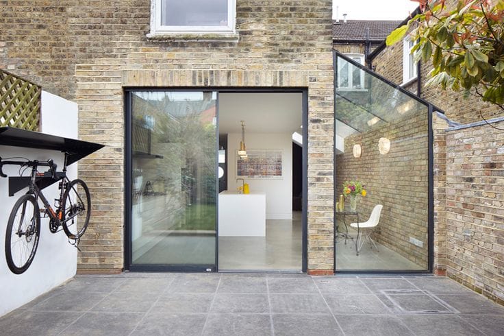 Glazed rear extension on a brick house, with a bicycle mounted on the wall beside it