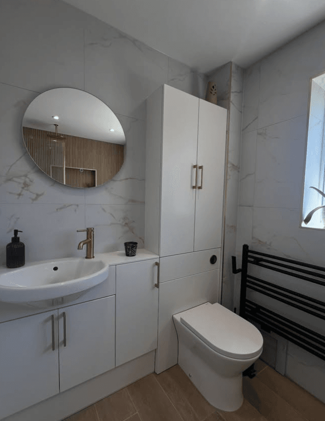 Bathroom with marble-effect tiling, a vanity basin and gold tap