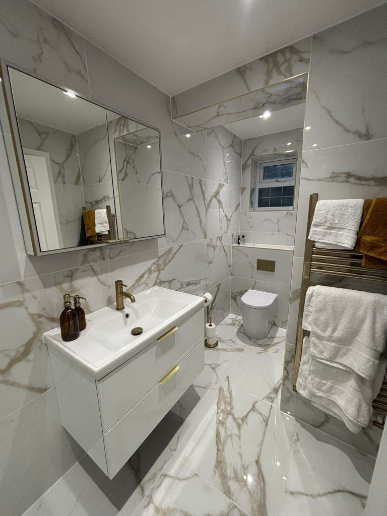 Bathroom with marble-effect tiling, a vanity basin and a gold tap