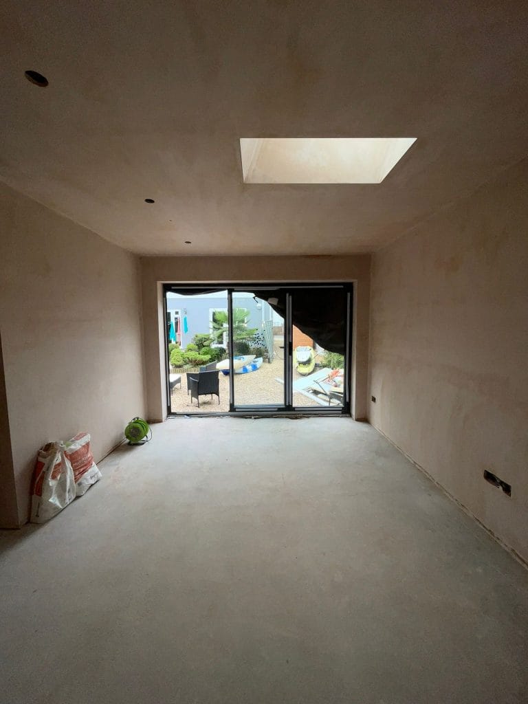 Interior under construction with a plastered ceiling and glazed doors to a terrace